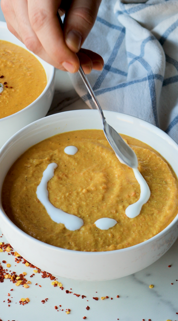 To make this creamy red lentil soup, begin by sautéing onions and minced garlic in oil. Then add carrots and seasonings. Cook for a few minutes, then add tomato paste, red lentils, and water. Bring to a boil, then cover and cook on super low for 30 minutes, or until lentils and carrots are soft. Blend until smooth, then add heavy cream. Add more heavy cream if a more soupy consistency is desired. Top with red pepper flakes and cilantro and enjoy!